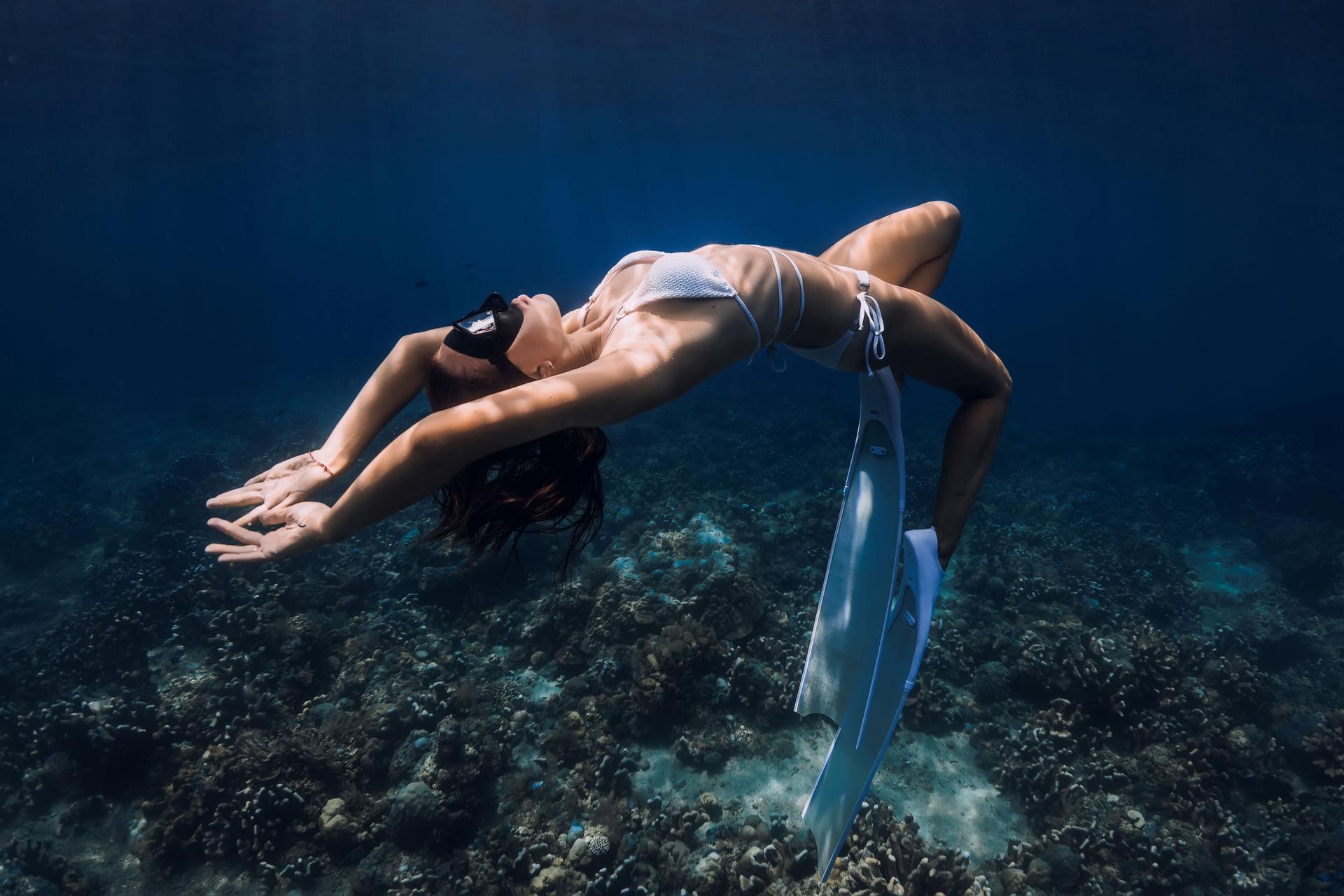 Underwater portrait of beautiful free diver woman in blue ocean.