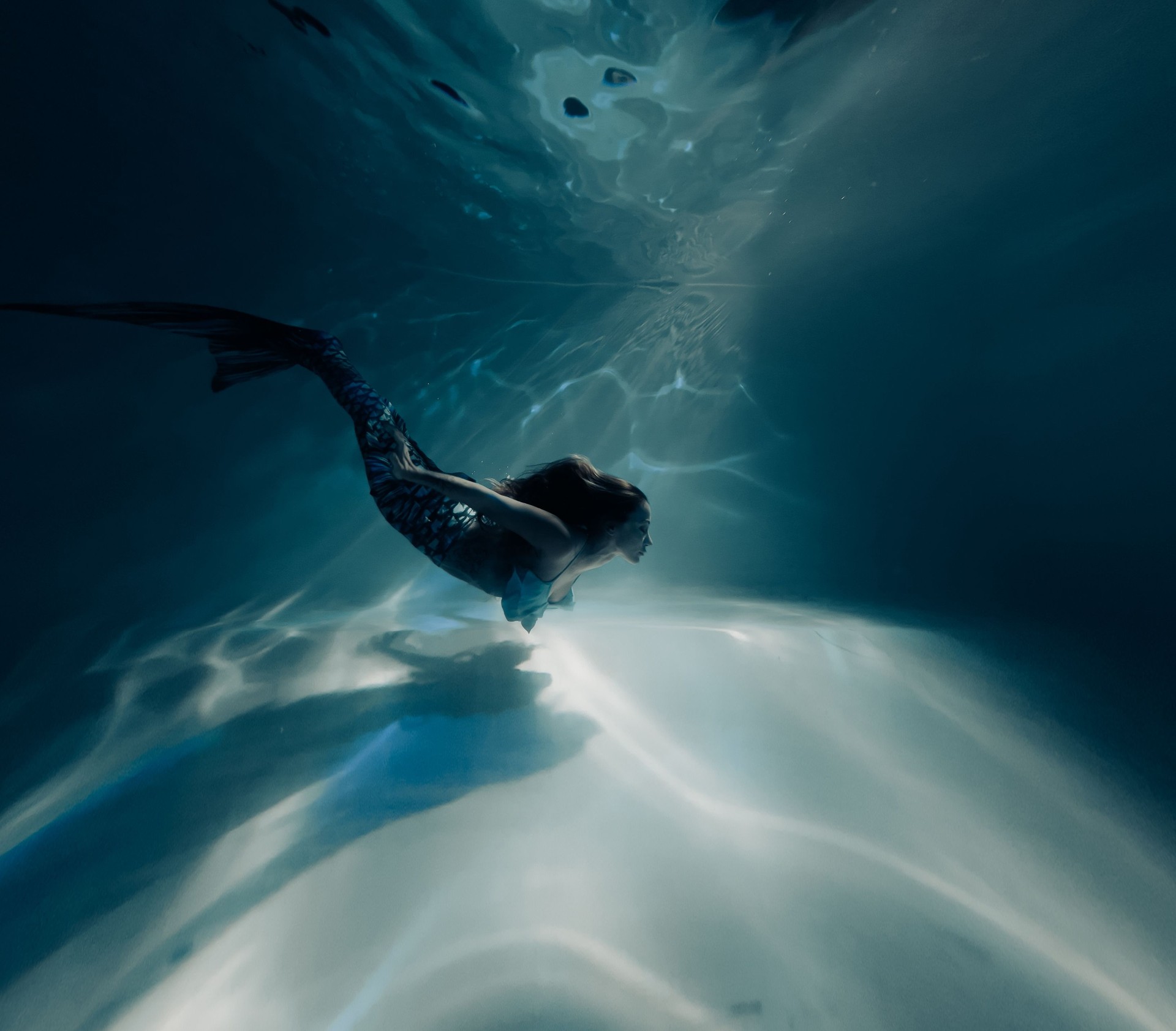 Woman with mermaid tail swims and dives underwater.